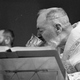Black-and-white photo of Catholic priest drinking the Sacramental wine